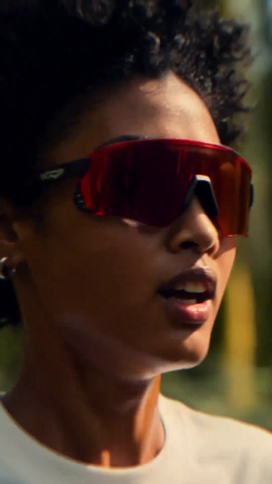 A runner wearing red sports sunglasses in warm forest light