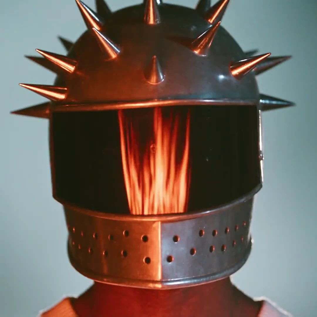 A figure wearing sculptural metallic headwear in dramatic light